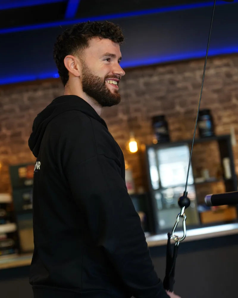 Personal Trainer Roel lacht naar cliënt in de privé zaal.